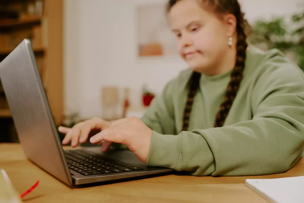 A young woman with down syndrome is making an enquiry to Coastal Care Queensland using her laptop
