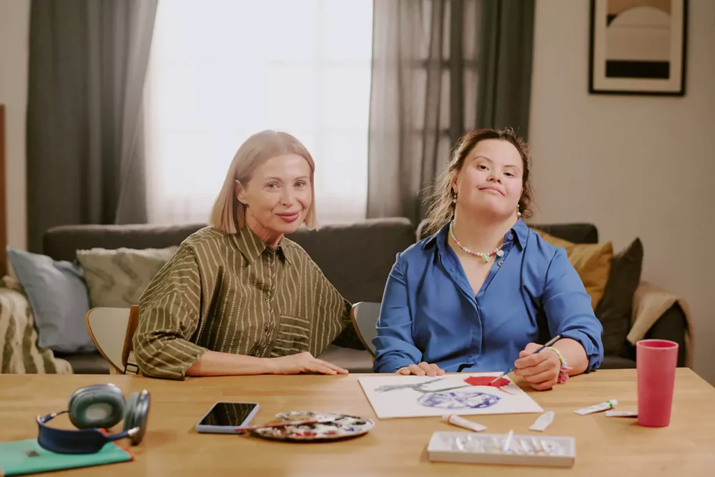 A young woman with down syndrome and her support worker are spending time together while painting